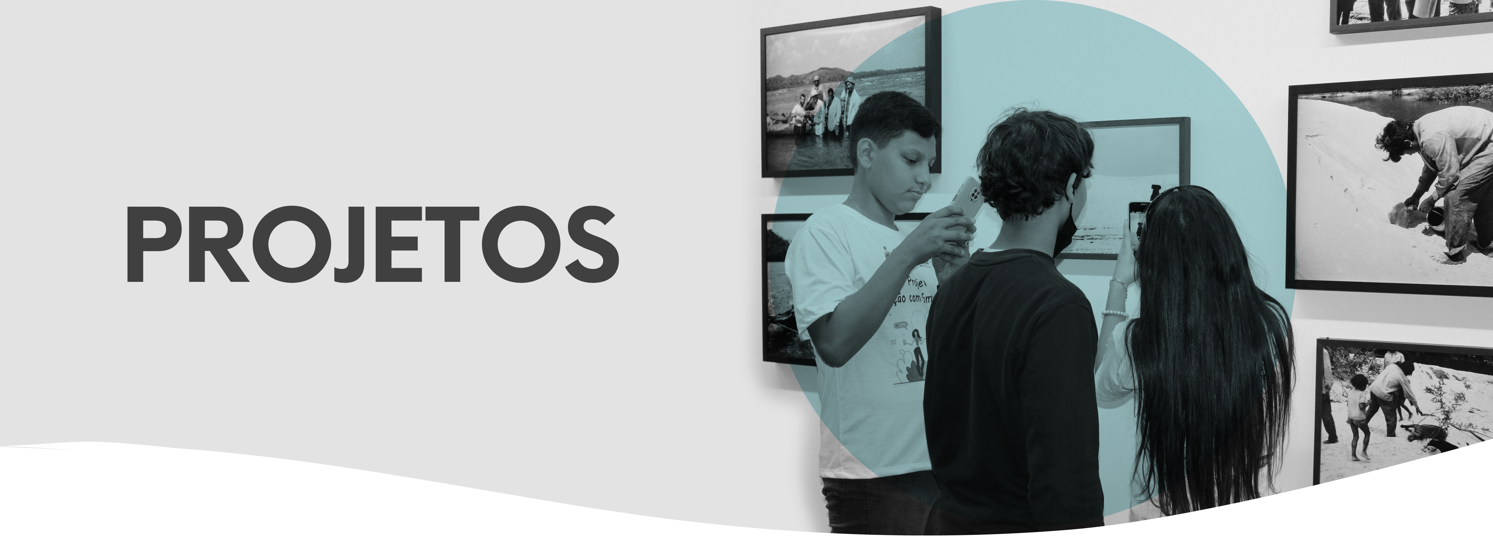 Banner com título Projetos escrito em caixa alta, com letras em negrito e na cor cinza. No canto direito, uma foto em preto e branco, de três adolescentes tirando fotos com o celular de quadros que estão na parede. Fundida com a foto, um elemento circular decorativo na cor azul claro.